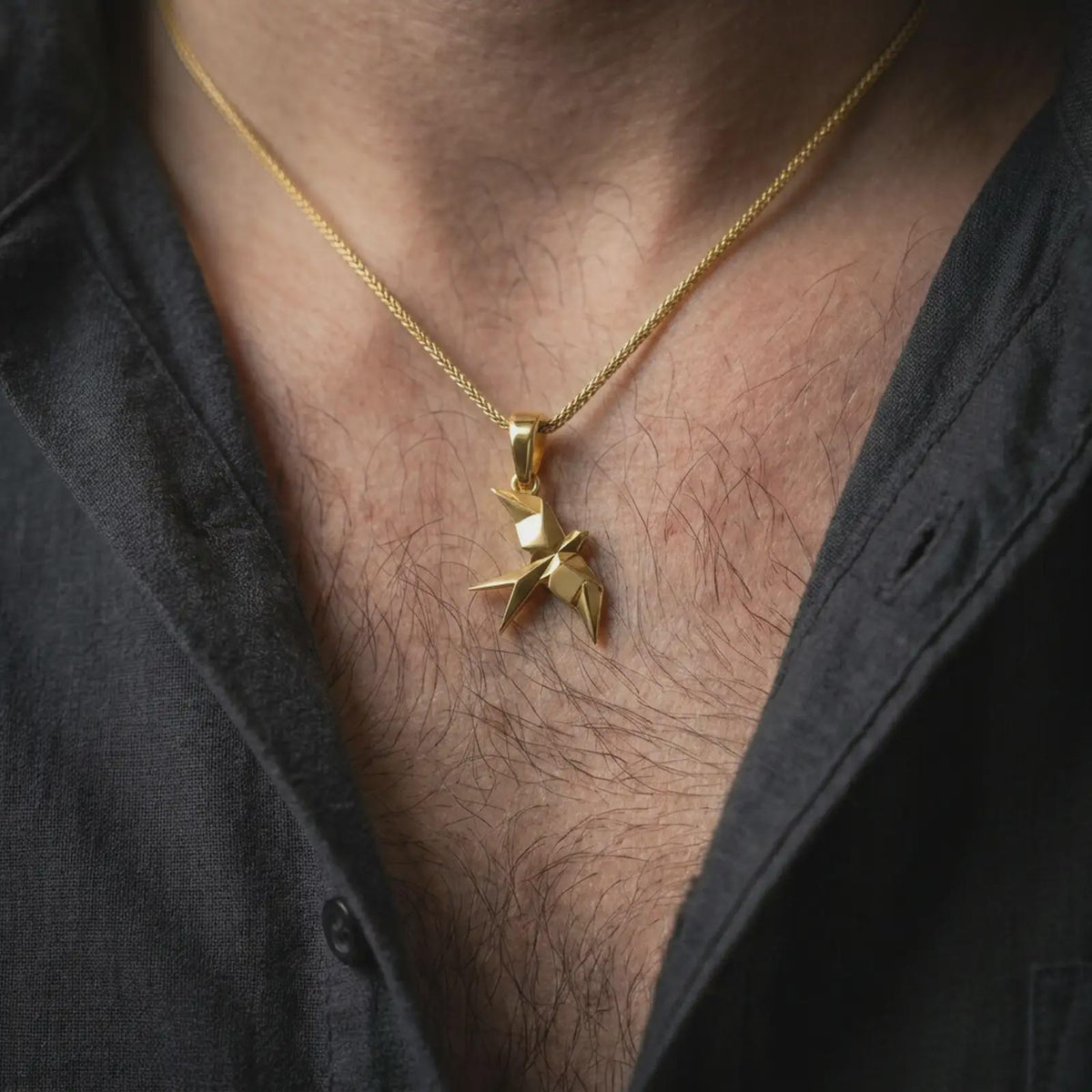 Gold plated swallow necklace worn on the chest, highlighting the origami-inspired bird form, angular wings, and symbolic freedom-inspired jewelry design.