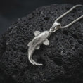 Load image into Gallery viewer, Polished sterling silver koi necklace displayed on dark volcanic stone, highlighting the sculpted carp body, engraved scale pattern, flowing fins, and graceful swimming shape.
