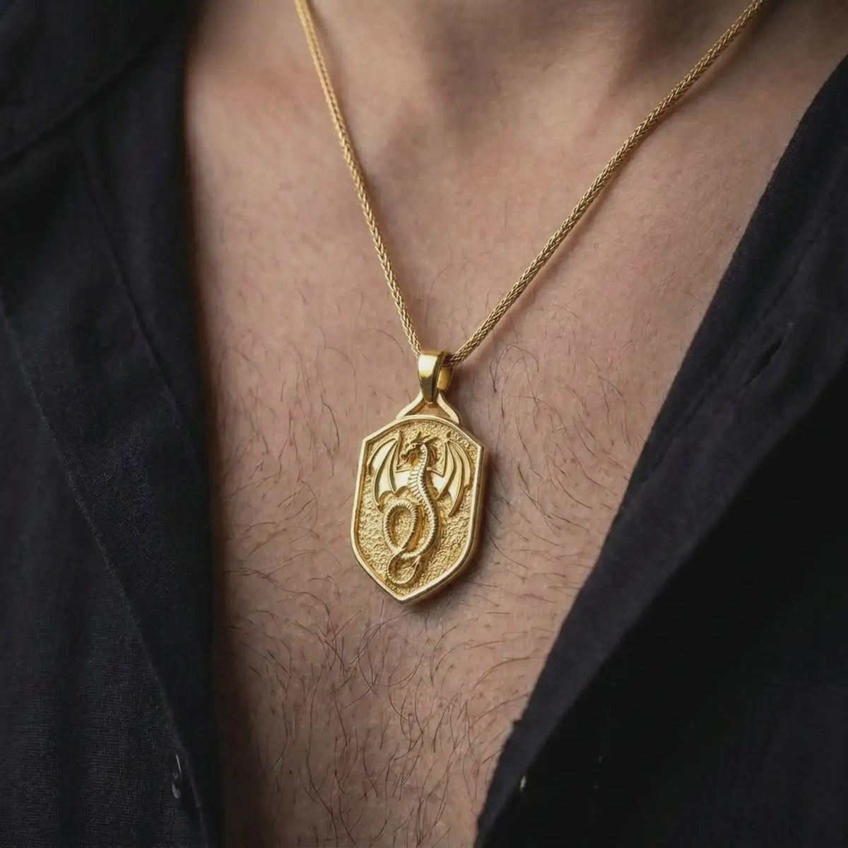 Gold plated dragon shield necklace worn on the chest, highlighting the winged dragon, coiled body, medieval crest shape, and powerful fantasy jewelry aesthetic.