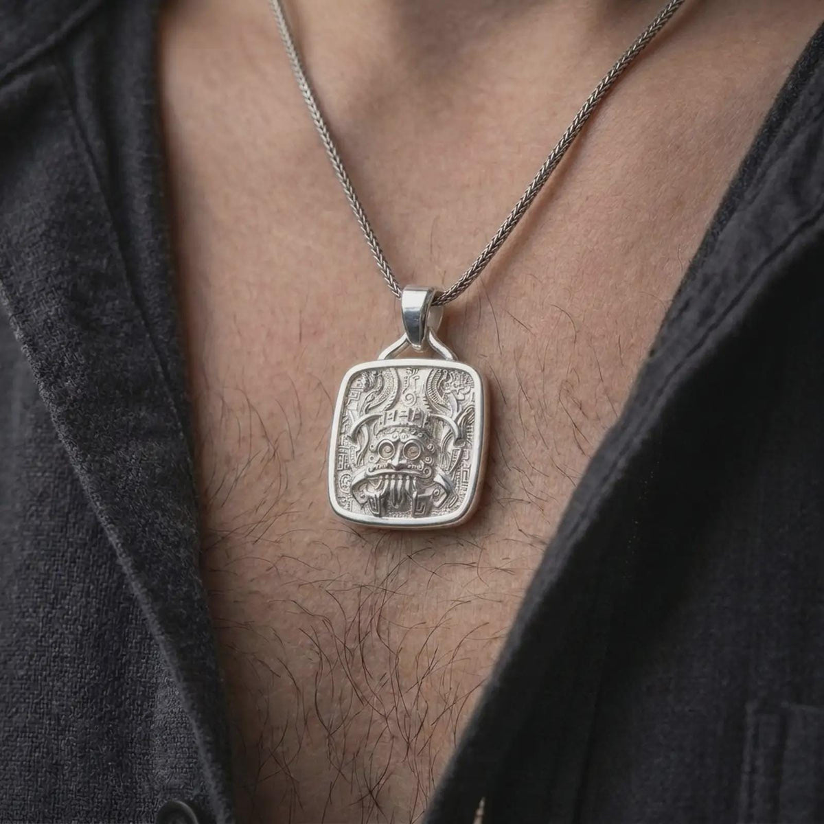 Polished silver Aztec Tlaloc pendant worn on the chest, featuring the rain god face, ceremonial ornamentation, bold fangs, and detailed Mesoamerican symbolism.