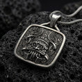 Load image into Gallery viewer, Oxidized sterling silver Tlaloc pendant on black volcanic rock, featuring ringed eyes, prominent fangs, curled facial details, and intricate Aztec geometric patterns.
