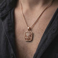 Load image into Gallery viewer, Rose gold plated Tlaloc pendant worn on the chest, showcasing the Mexica rain deity, ornate headdress, goggle eyes, fangs, and ancient Mesoamerican-inspired details.
