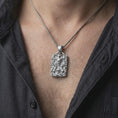 Load image into Gallery viewer, Polished silver ram horn skull pendant worn on the chest, featuring a detailed demon skull, surrounding skeletal hands, flames, and a bold masculine gothic design.
