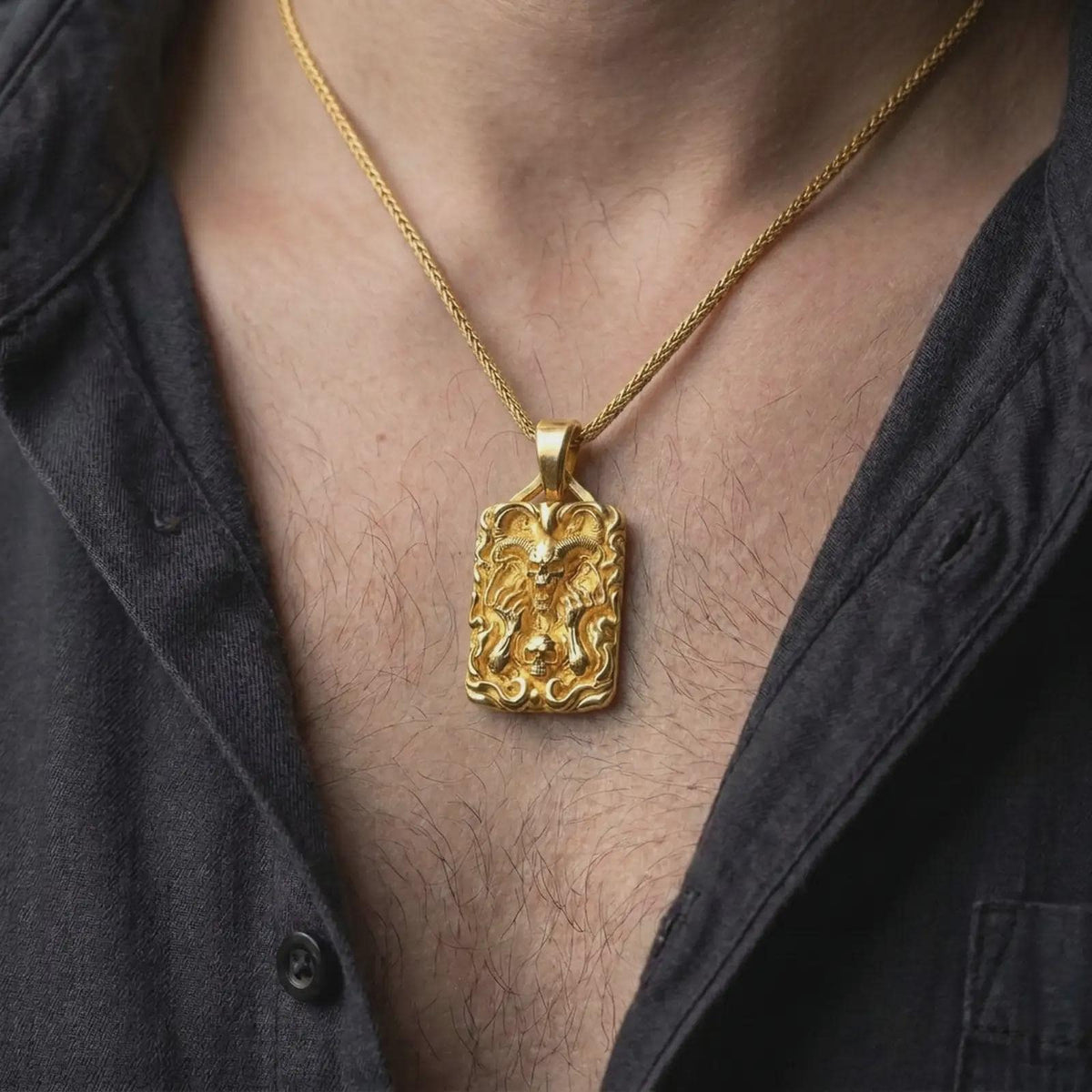 Gold plated demon skull necklace worn on the chest, highlighting the curled ram horns, open skull face, skeletal details, and dramatic biker-inspired styling.