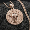 Load image into Gallery viewer, Rose gold plated Odin pendant displayed on textured volcanic stone, showcasing the fantasy Viking helmet, rune-style symbols, engraved lettering, and Nordic warrior aesthetic.
