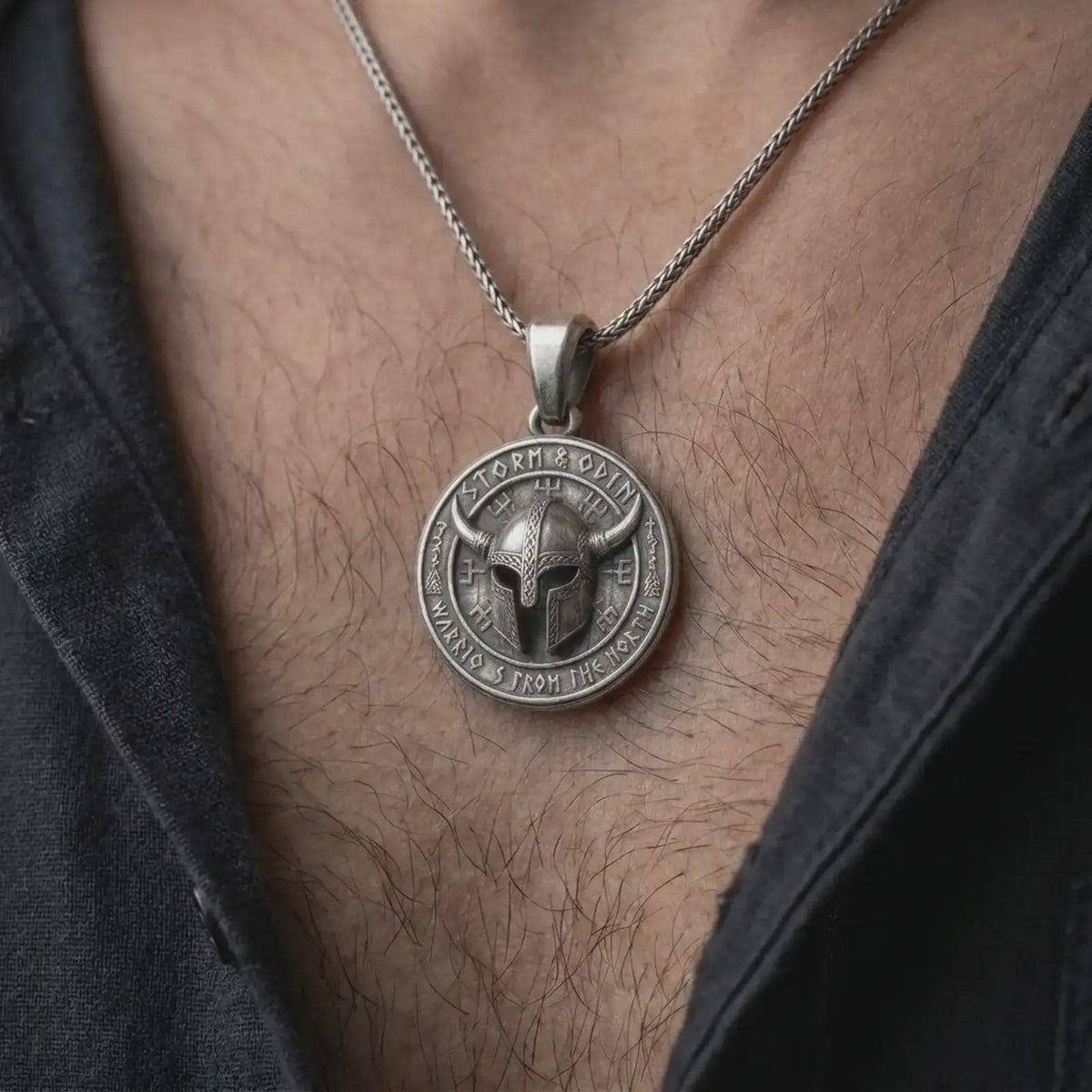 Oxidized sterling silver Viking necklace worn on the chest, displaying the horned helmet centerpiece, Norse symbols, Storm and Odin lettering, and bold round pendant profile.