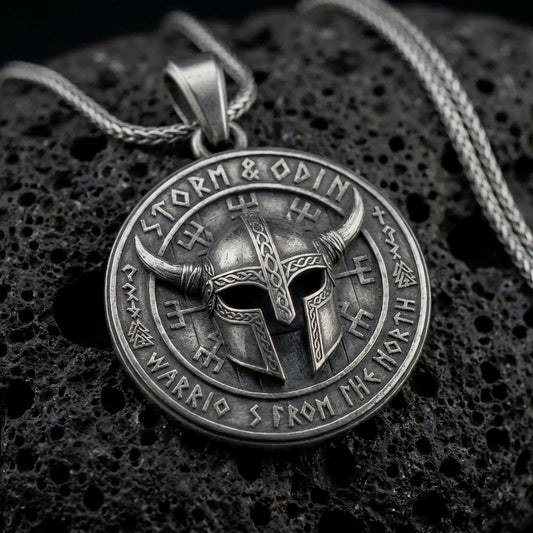 Oxidized sterling silver Viking helmet pendant on black volcanic rock, featuring a horned warrior helmet, Storm and Odin lettering, and Norse-inspired rune symbols.