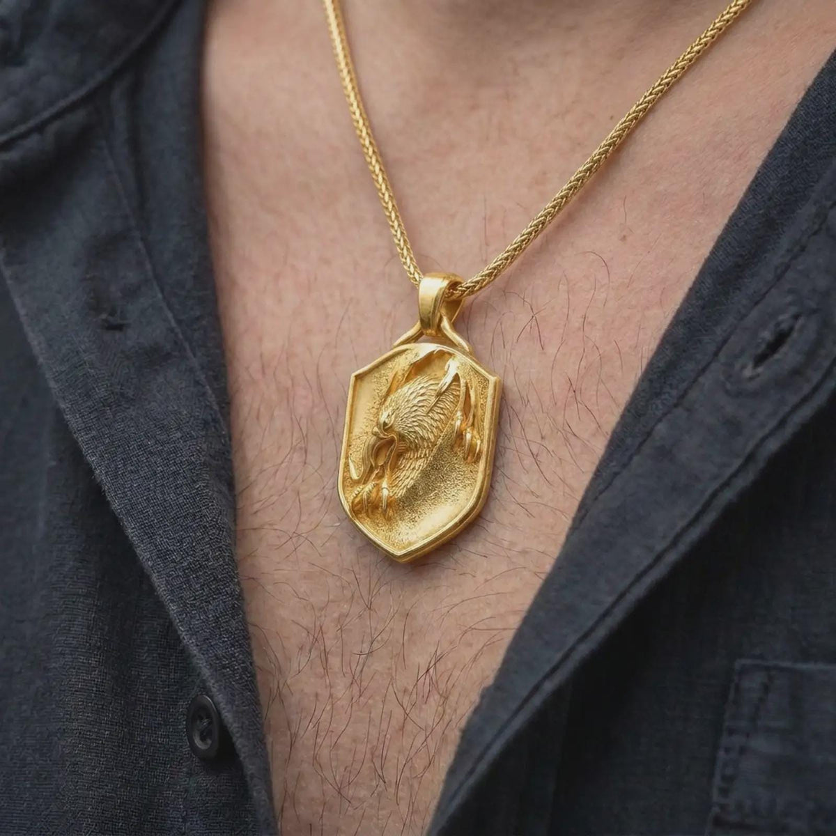 Gold plated eagle necklace worn on the chest, highlighting the detailed eagle head, layered plumage, sharp talons, and strong heraldic shield aesthetic.