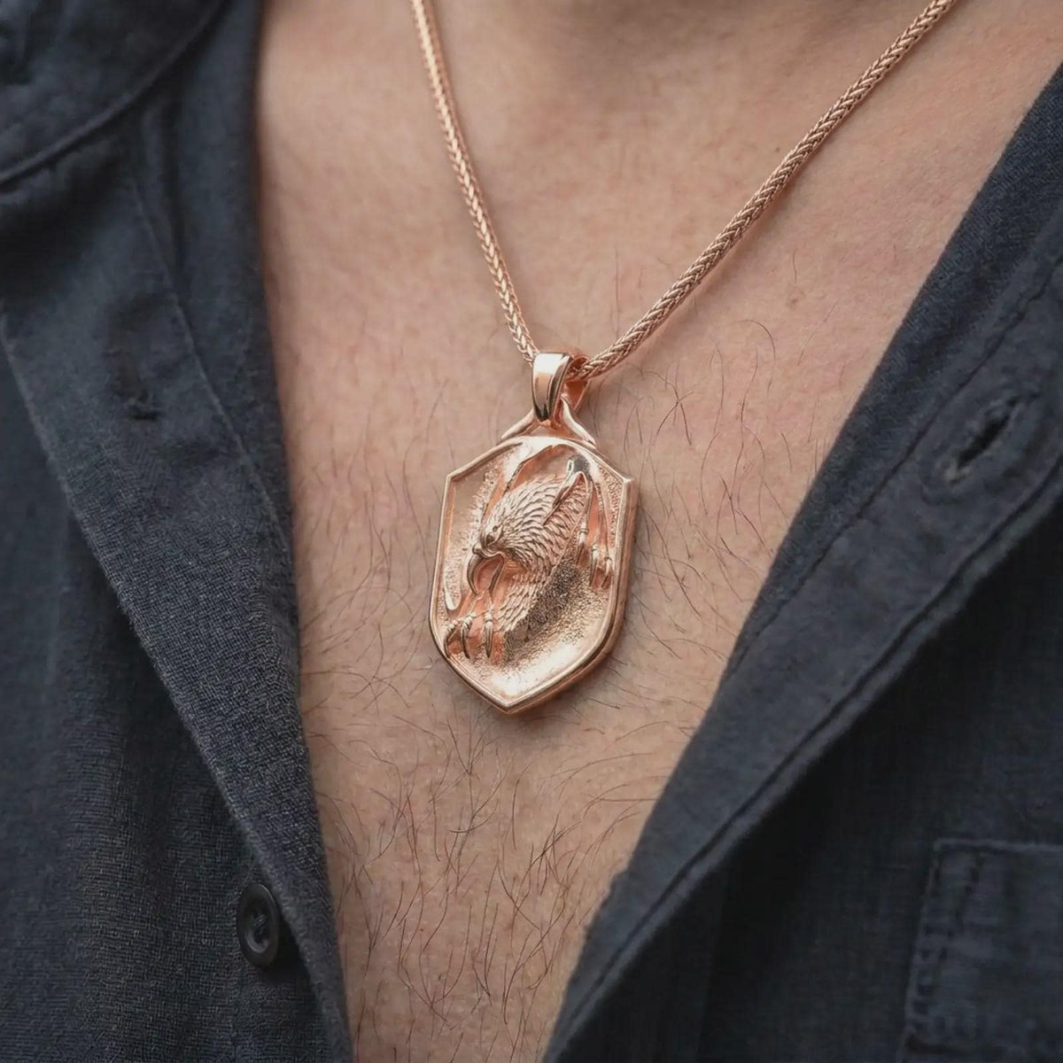 Rose gold plated eagle shield pendant worn on the chest, showcasing the bird of prey design, sculpted feathers, curved claws, and meaningful statement jewelry style.