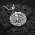 Load image into Gallery viewer, Polished sterling silver Lovecraft necklace displayed on textured volcanic stone, highlighting the circular pendant shape, tentacled Cthulhu motif, and engraved mythos-inspired border text.
