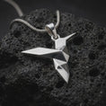 Load image into Gallery viewer, Polished sterling silver hummingbird necklace displayed on dark volcanic stone, highlighting the minimalist origami bird form, sharp edges, and modern sculptural silhouette.

