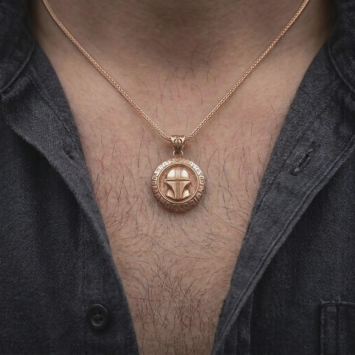 Rose gold plated Mandalorian helmet pendant worn on the chest, showcasing the raised bounty hunter helmet, engraved lettering, symbolic insignia bail, and bold space fantasy necklace aesthetic.