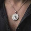 Load image into Gallery viewer, Polished silver half-skull face pendant worn on the chest, featuring the classical human and skull transformation, cracked stone relief, circular Roman clock details, and Stoic philosophy jewelry styling.
