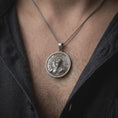 Load image into Gallery viewer, Oxidized sterling silver Memento Mori necklace worn on the chest, showing the half-human half-skeleton portrait, engraved Memento Mori inscription, Roman numeral markings, and distinctive gothic medallion design.
