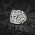 Load image into Gallery viewer, Polished sterling silver Jesus and two thieves ring displayed on dark volcanic stone, highlighting the three crosses, Christ figure, Jerusalem architecture, and detailed Christian signet design.
