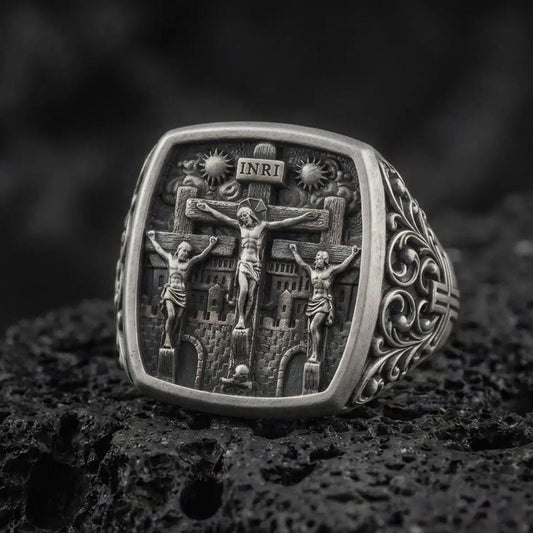 Oxidized sterling silver Crucifixion ring on black volcanic rock, featuring Jesus Christ on the center cross between the two thieves, INRI inscription, and detailed Calvary scene.