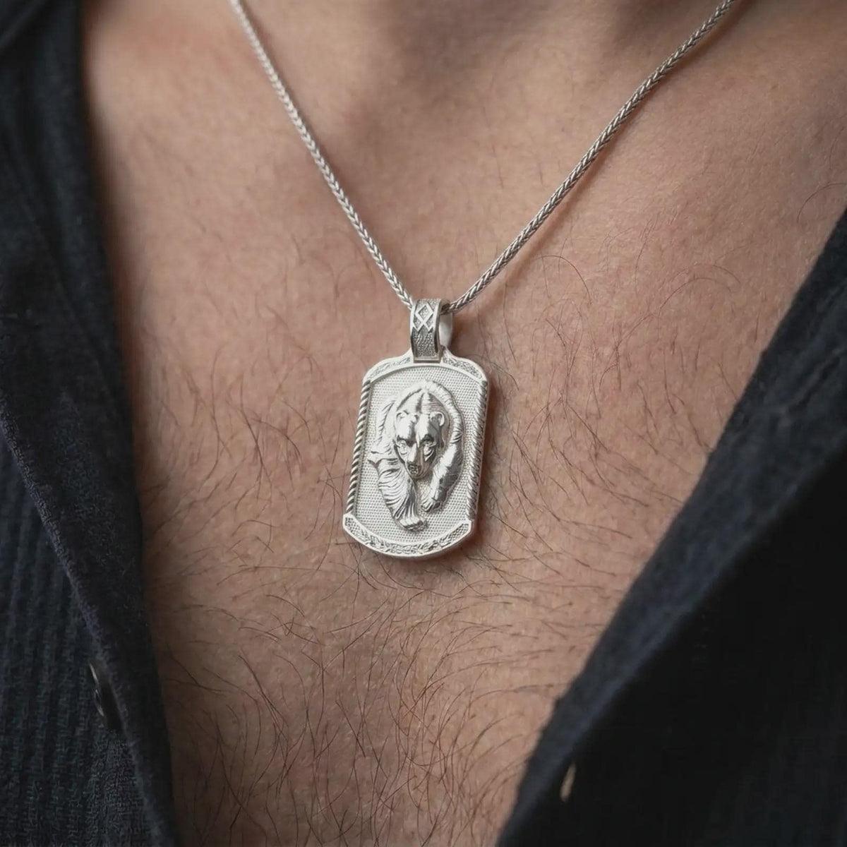 Polished silver grizzly bear and cub pendant worn on the chest, featuring sculpted wildlife details and a meaningful parent-child bond in a rugged dog tag necklace.