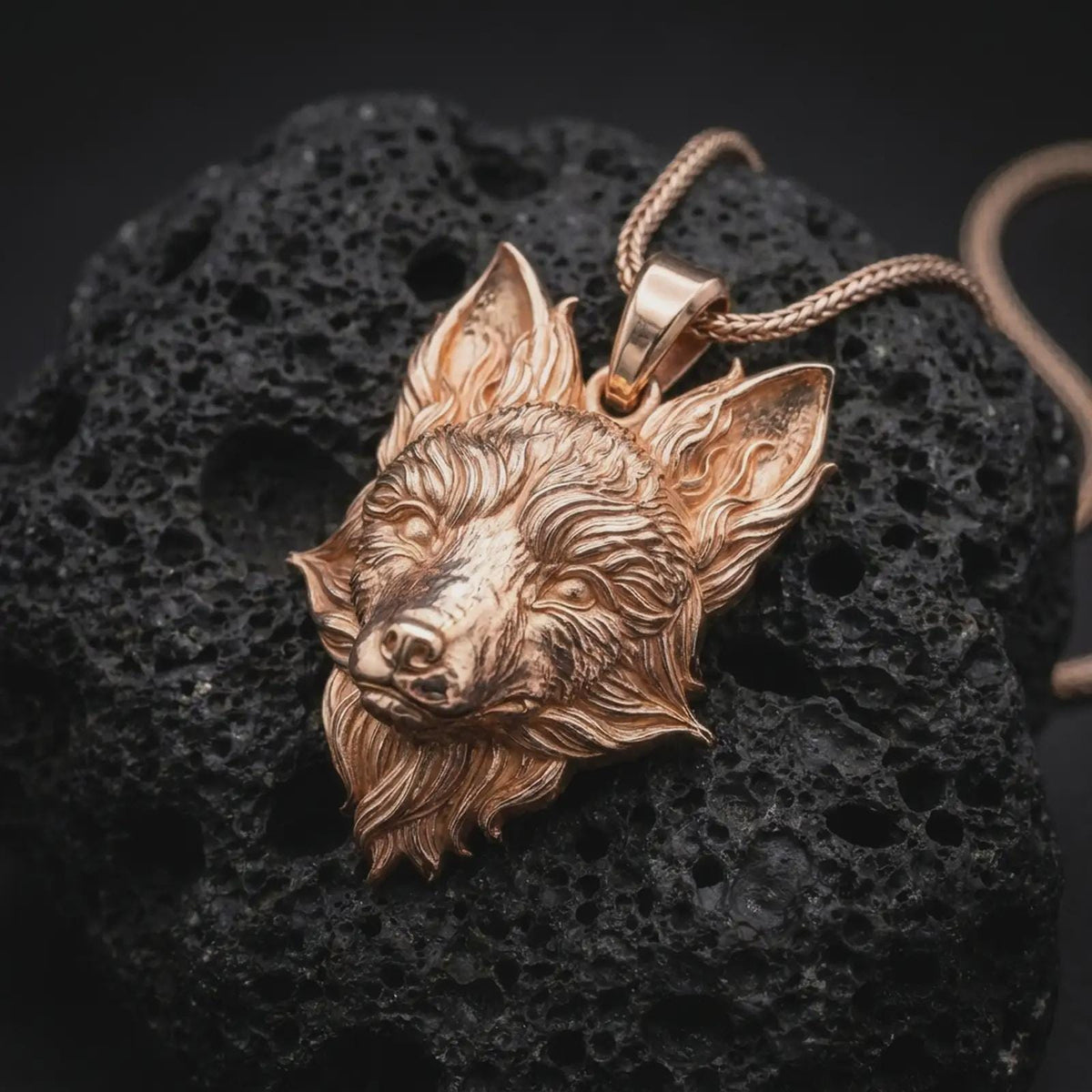 Rose gold plated fox necklace displayed on textured volcanic stone, showcasing the expressive fox face, flowing fur, sharp ears, and dimensional wildlife pendant profile.