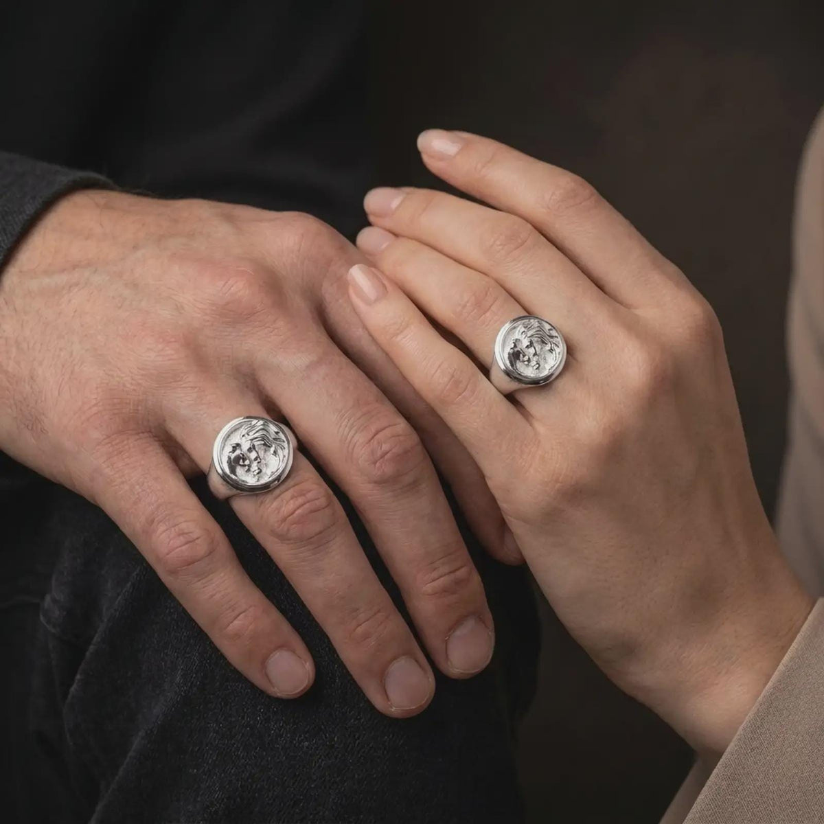 Polished silver lion lioness and cub signet ring worn on the hand, featuring the three sculpted animal portraits, textured background, and symbolic family unity jewelry design.