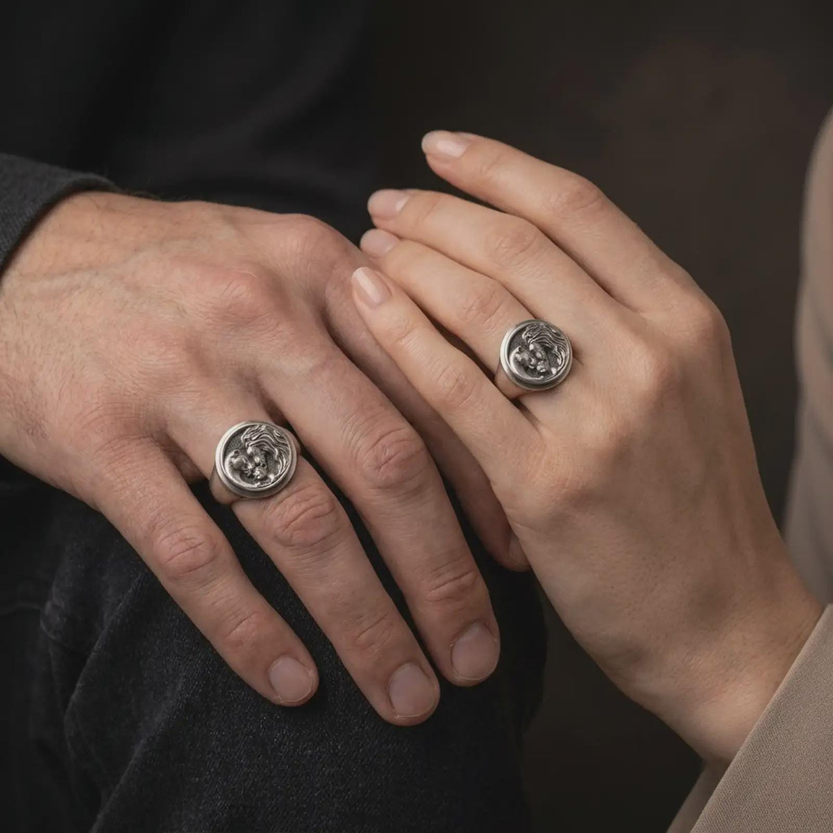 Oxidized sterling silver lion family ring worn on the finger, showing the male lion with flowing mane, lioness leaning toward their cub, and detailed circular signet face symbolizing fatherhood.