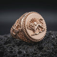 Load image into Gallery viewer, Rose gold plated Persian heritage ring displayed on textured volcanic stone, showcasing the dimensional lion and sun emblem, elaborate ornamental shoulders, twisted rope bezel, and traditional Iranian symbolism.
