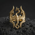 Load image into Gallery viewer, Gold plated Skyrim-inspired Dragonborn ring resting on black volcanic rock, featuring the legendary dragon emblem, symmetrical angular wings, curled serpentine body, and distinctive openwork fantasy jewelry design.
