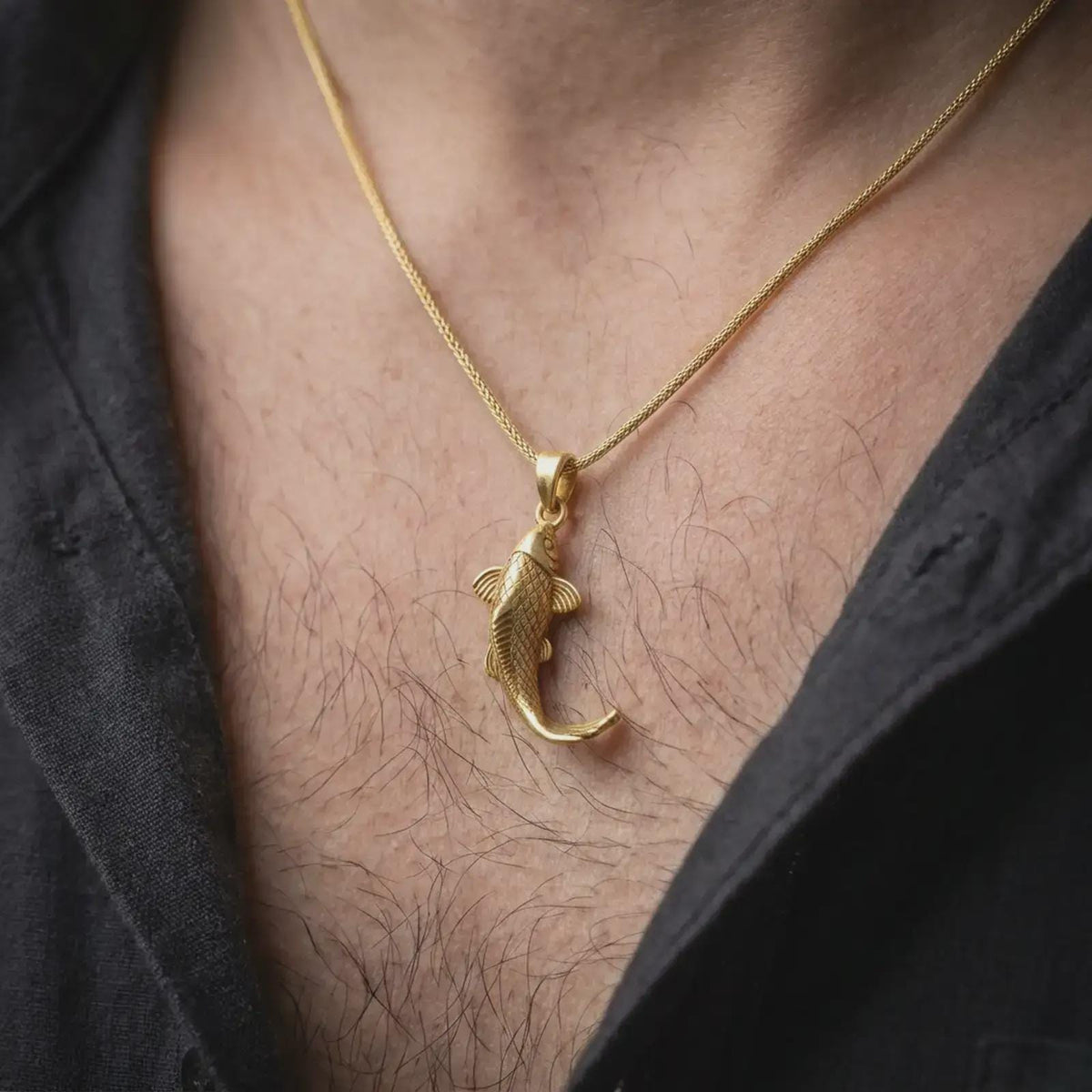 Gold plated koi fish necklace worn on the chest, highlighting the detailed carp shape, textured scales, flowing tail, and meaningful good luck jewelry design.