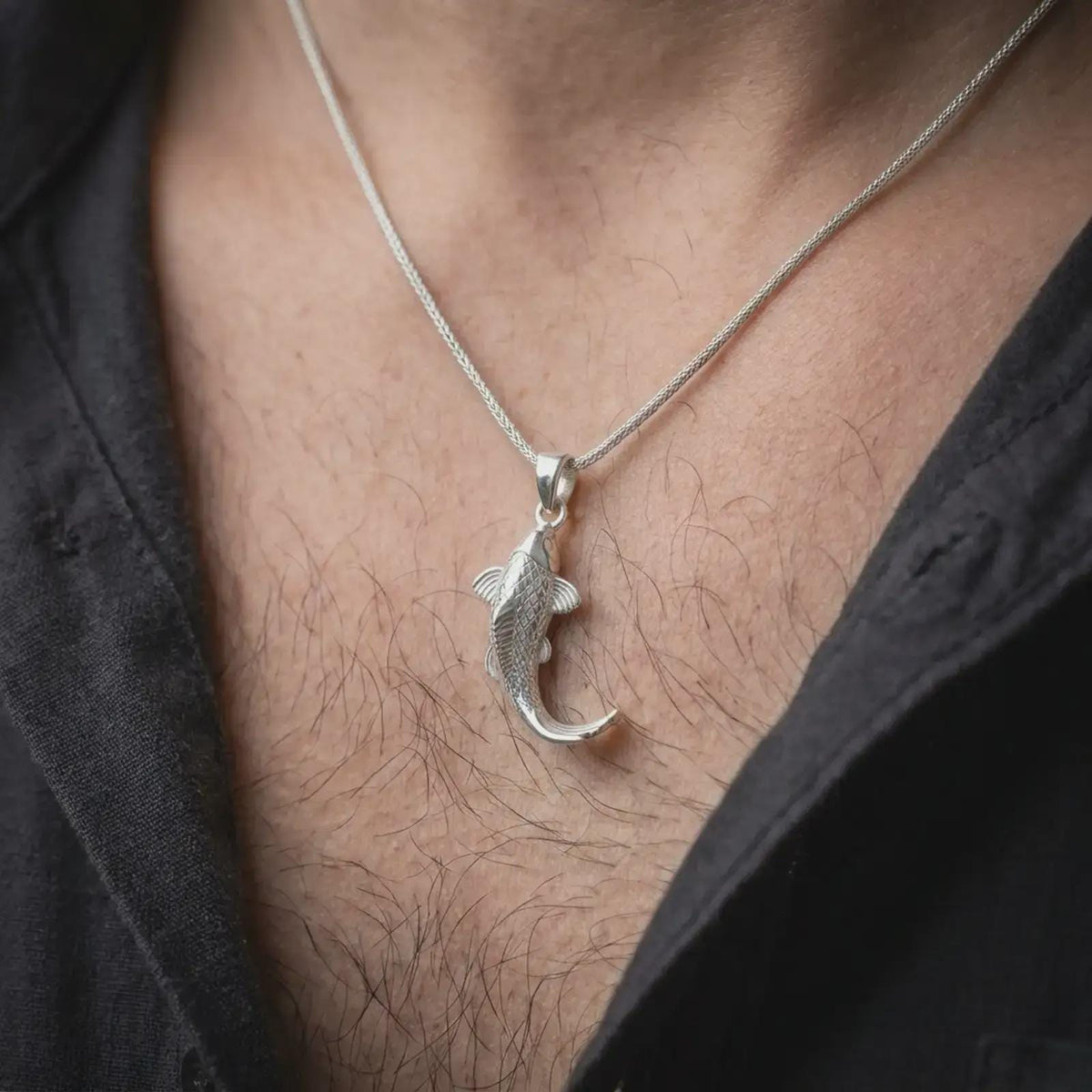 Polished silver Japanese koi pendant worn on the chest, featuring engraved fish scales, a graceful curved tail, sculpted fins, and elegant nature-inspired styling.