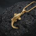 Load image into Gallery viewer, Gold plated Japanese koi fish pendant resting on black volcanic rock, featuring detailed scales, curved tail, sculpted fins, and an elegant lucky carp design.
