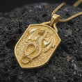 Load image into Gallery viewer, Gold plated coiled dragon pendant resting on black volcanic rock, featuring sweeping wings, detailed scales, curled tail, and a bold medieval fantasy shield design.
