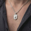 Load image into Gallery viewer, Polished silver leopard necklace worn on the chest, featuring the dimensional spotted leopard sculpture, focused expression, extended front paws, textured medallion background, and substantial silver pendant bail.
