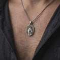 Load image into Gallery viewer, Oxidized sterling silver horse head necklace worn around the neck, showing the raised equestrian horse portrait, detailed bridle, flowing mane, dark recessed shield-shaped face, and braided silver chain.
