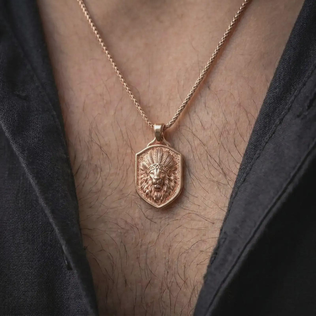 Rose gold plated lion chief pendant worn on the chest, showcasing the three-dimensional lion portrait with a feathered ceremonial-style headdress, intricate mane details, textured shield-shaped frame, and distinctive symbolic warrior jewelry aesthetic.