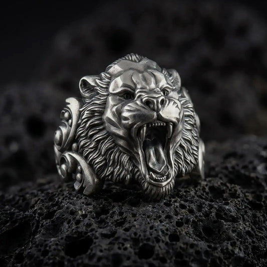 Oxidized sterling silver roaring tiger ring displayed on black volcanic stone, featuring an open mouth, sharp fangs, detailed fur texture, and bold sculptural side accents.