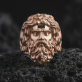 Load image into Gallery viewer, Rose gold plated sterling silver Poseidon ring resting on black volcanic stone, showcasing the dimensional Greek mythology god portrait, detailed facial anatomy, flowing beard, sculpted hair, and elegant rose gold finish.
