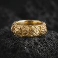 Load image into Gallery viewer, Gold plated sterling silver rose flower band ring displayed on dark volcanic rock, featuring detailed three-dimensional roses, overlapping petals, botanical leaf engravings, and a warm gold plated finish.
