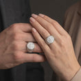 Load image into Gallery viewer, Polished white gold matching Saint Benedict signet rings worn on the fingers of a man and woman together, showcasing detailed Benedictine Cross medallions, PAX inscriptions, decorative Celtic knot patterns, and matching polished silver finishes.
