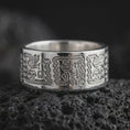 Load image into Gallery viewer, Polished 925 sterling silver Aztec Mayan wedding band resting on black volcanic stone, showcasing detailed ancient-inspired symbols, stylized human figures, repeating zigzag borders, and a bright polished silver finish.
