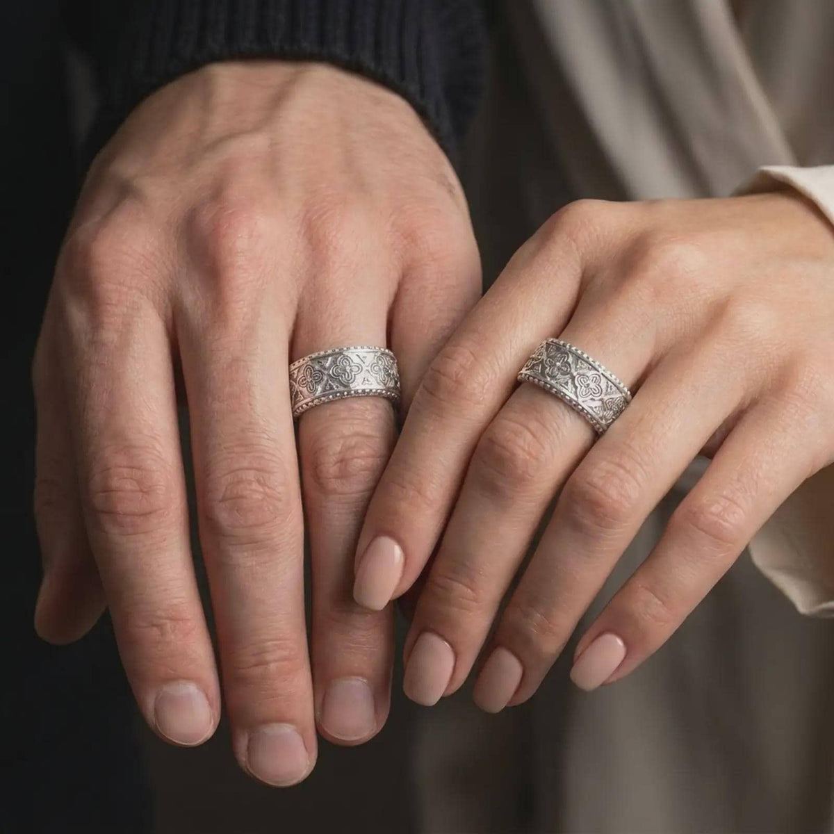 Polished 925 sterling silver matching Viking Valknut rings worn on the fingers of a man and woman together, showcasing repeating interlocking triangle motifs, geometric patterns, and matching bright polished silver finishes.