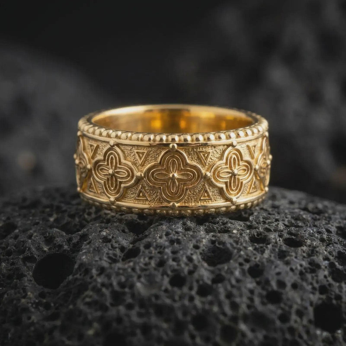 Gold plated 925 sterling silver Viking Valknut ring displayed on dark volcanic rock, featuring raised interlocking triangle symbols, repeating Nordic geometric patterns, smooth band edges, and a warm polished gold finish.