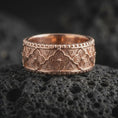 Load image into Gallery viewer, Rose gold plated 925 sterling silver Norse Valknut band resting on black volcanic stone, highlighting repeating triangular symbols, geometric engravings, textured recesses, and a warm rose gold finish.
