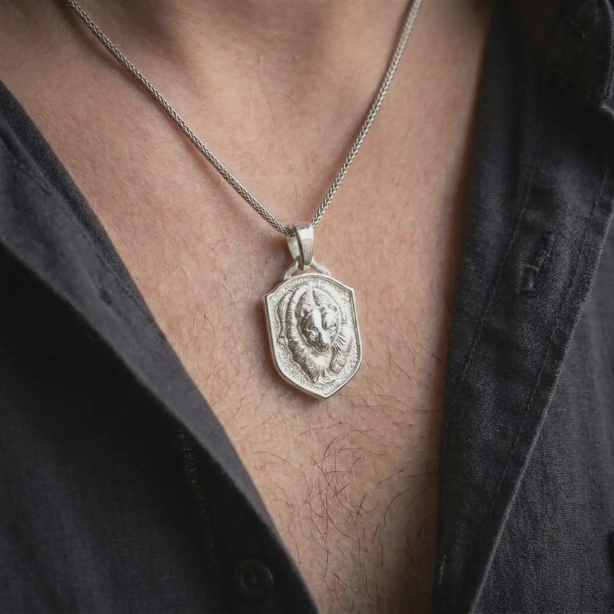 Polished silver bear shield pendant worn on the chest, featuring a dimensional grizzly head, sculpted fur relief, and bold wildlife statement necklace design.