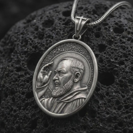 Oxidized sterling silver Padre Pio pendant on black volcanic rock, featuring Saint Pio of Pietrelcina with a raised blessing hand, detailed beard, halo, and traditional Franciscan habit.