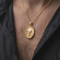 Load image into Gallery viewer, Gold plated Padre Pio medal necklace worn on the chest, highlighting the raised blessing hand, sculpted beard, saintly halo, and meaningful Christian devotional pendant styling.
