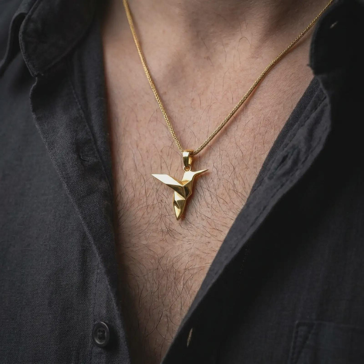 Gold plated origami bird necklace worn on the chest, highlighting the stylized hummingbird shape, folded metal effect, and sleek modern animal jewelry aesthetic.