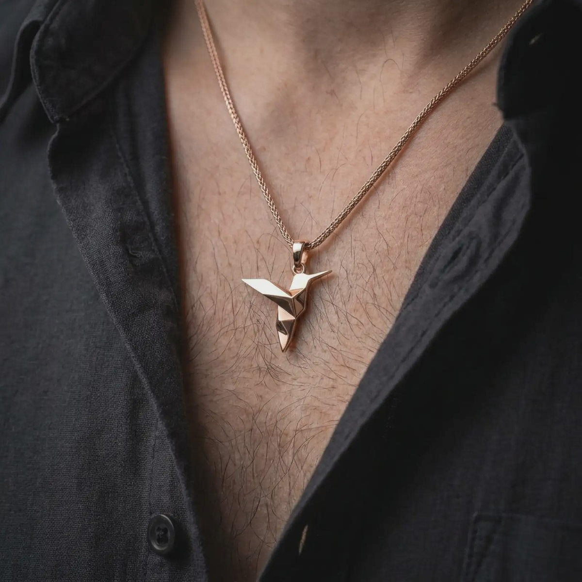 Rose gold plated origami hummingbird charm worn on the chest, showcasing the geometric bird form, sculptural pointed wings, and elegant minimalist necklace design.