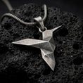 Load image into Gallery viewer, Oxidized sterling silver origami hummingbird pendant on black volcanic rock, featuring a geometric folded bird design with a long pointed beak and angular wings.
