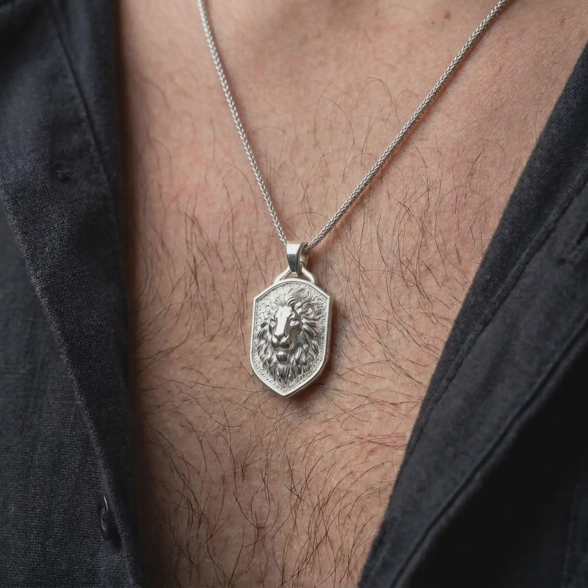 Polished silver regal lion pendant worn on the chest, featuring a detailed lion face, flowing sculpted mane, and distinctive heraldic shield necklace design for men.