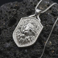 Load image into Gallery viewer, Polished sterling silver lion head necklace displayed on dark volcanic stone, highlighting the sculpted lion face, expressive eyes, detailed flowing mane, and shield-shaped medallion frame.
