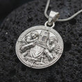 Load image into Gallery viewer, Polished sterling silver guardian knight necklace displayed on dark volcanic stone, highlighting the medieval warrior embracing two children, detailed plate armor, sword, and Christian cross symbols.
